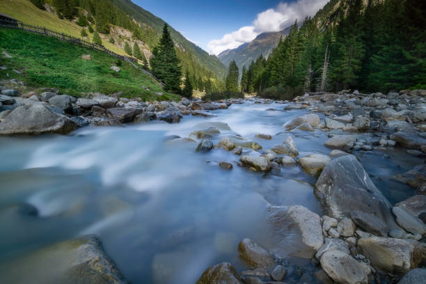 View of the flowing river Ruetz with stones and trees in the background from Stubai / Austria /