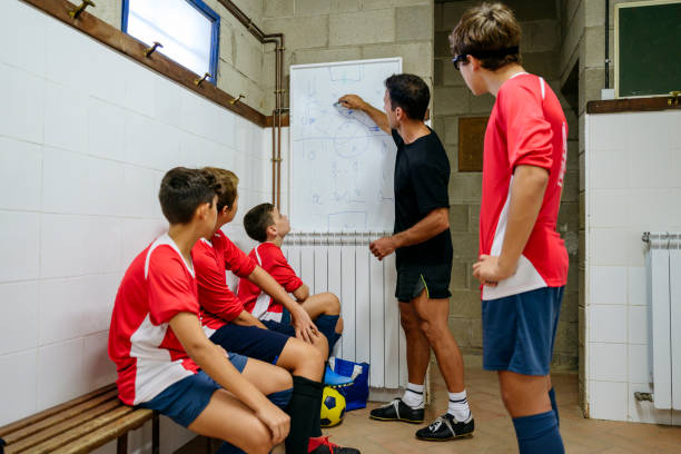 istock Young footballers watching coach draw diagrams on whiteboard 1189767793
