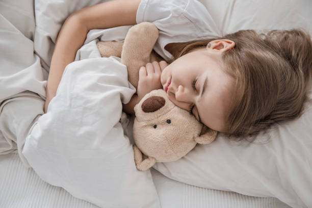 istock Cute little girl in bed with soft toy. 1189770593