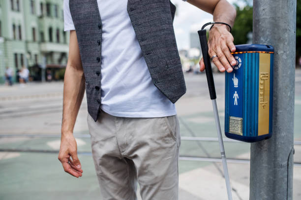 Midsection of young blind man with white cane walking across the street in city. Midsection of young unrecognizable blind man with white cane walking across the street in city. aids walk stock pictures, royalty-free photos & images