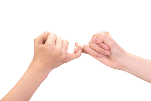 Close-up shot of two unrecognizable little boy making a pinky swear as a promise to one another over white background. Horizontal composition, studio shot.