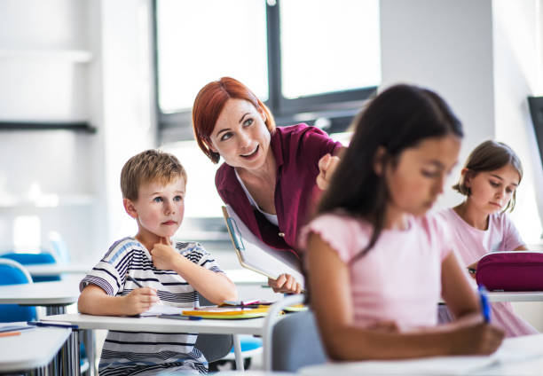 istock A teacher walking among small school children on the lesson, explaining. 1189773606