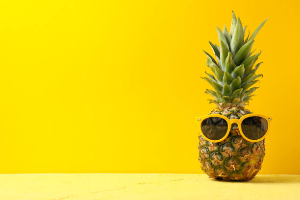 istock Pineapple with sunglasses on yellow background, space for text. Juicy fruit 1189774758