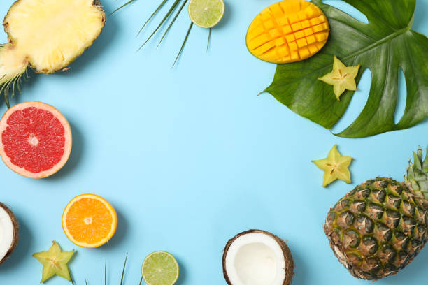 Exotic fruits and palm leaves on blue background, space for text