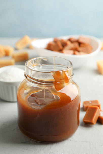 istock Glass jar with salted caramel and candies on grey background, space for text 1189775094