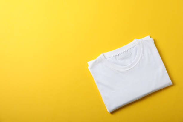 istock Folded blank white t-shirt on yellow background, space for text 1189776658
