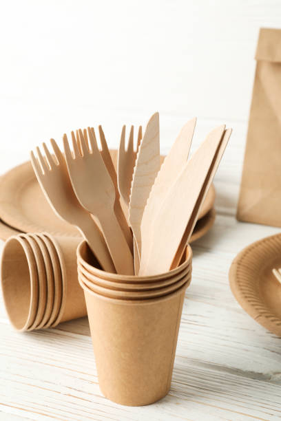 istock Eco - friendly tableware and paper bag on wooden table, space for text 1189779750