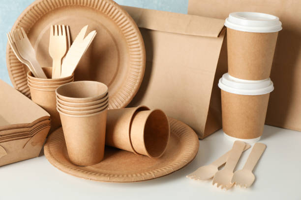 istock Eco - friendly tableware and paper bag on wooden table, close up 1189780379