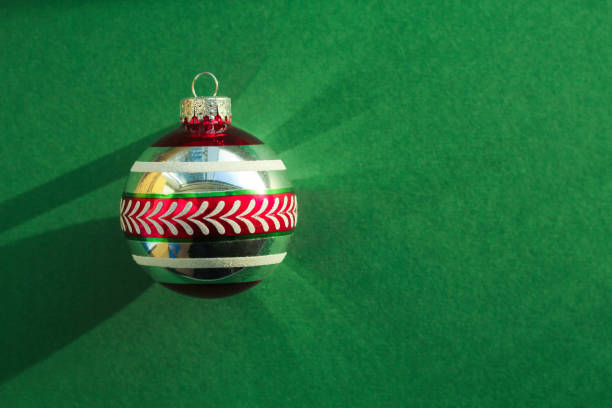 red-green Christmas tree toy on a green background with sunlight. space for text