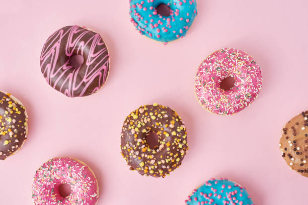 istock Pattern with different types of colorful donats decorated sprinkles and icing on a pastel pink background, top view flat lay 1189781579