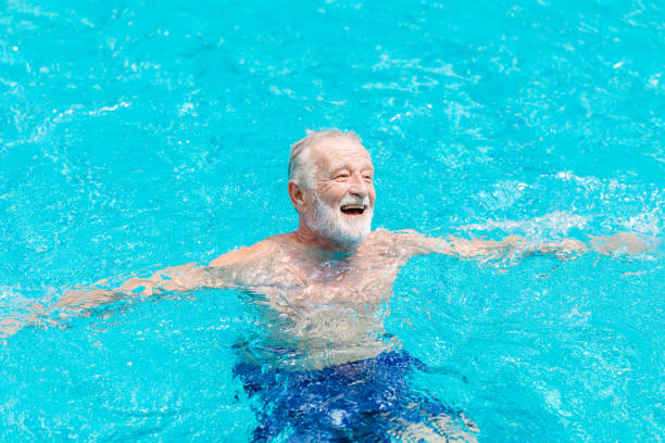 aîné en bonne santé heureux profiter et rire dans la piscine en saison estivale. - livestrong photos et images de collection