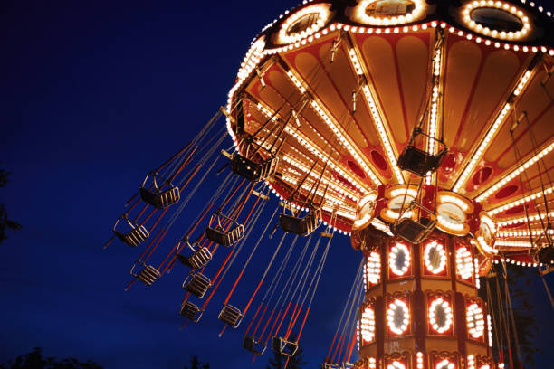 carrousel merry-go-round dans le parc d'attractions à une ville de nuit - ferris wheel wheel blurred motion amusement park photos et images de collection