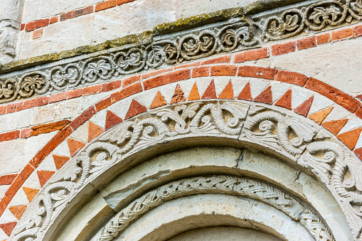 Montechiaro, Asti, Piedmont, Italy - July 21, 2019: Detail of external bas-reliefs of the Church of the Saints Nazario and Celso, an example of Romanesque architecture.