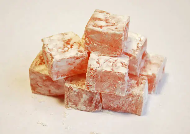 Photo of Turkish delight, lokum or rahat lokum is a family of confections based on a gel of starch and sugar. Small, fragrant cubes of jelly, usually flavoured with rose, mint, vanilla.White background