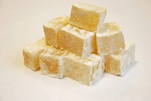 Photo of Turkish delight, lokum or rahat lokum is a family of confections based on a gel of starch and sugar. Small, fragrant cubes of jelly, usually flavoured with rose, mint, vanilla.White background