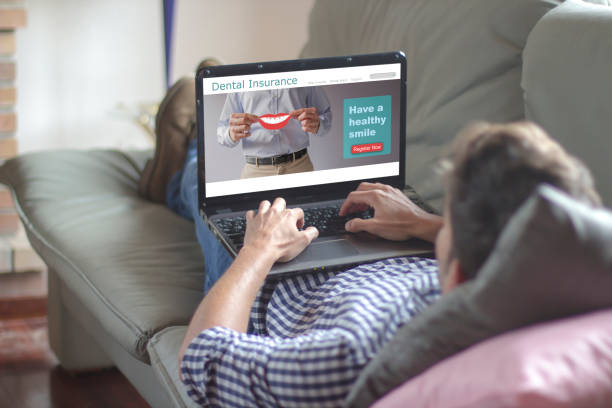 istock Man using laptop with dental insurance website on the screen 1189791377