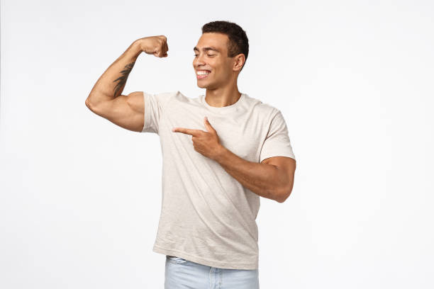 istock Satisfied, proud assertive young brazilian man with strong muscles, tense raised arm, smiling and pointing biceps proudly, delighted with own perfect body, workout in gym, showing results of sport 1189792777