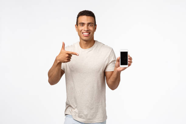istock Technology, mobile gadget and people concept. Cheerful good-looking brazilian athletic man recommend fitness app, looking at calories or diet advices, holding smartphone, pointing mobile, smiling 1189793014