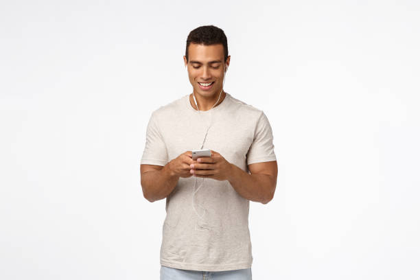 istock Communication, technology and mobile device concept. Handsome athletic man in casual outfit, wear earphones, hold smartphone and smiling looking mobile screen, message friend, watch video in subway 1189793286