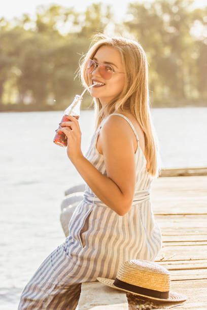 istock Cheerful young woman drinking soda lemonade at riverside 1189793955