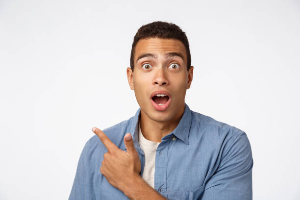 istock Enthusiastic, surprised hispanic man in blue shirt over t-shirt, pointing upper left corner, gasping and drop jaw amazed, popping eyes camera, impressed with new product, look astonished 1189794203