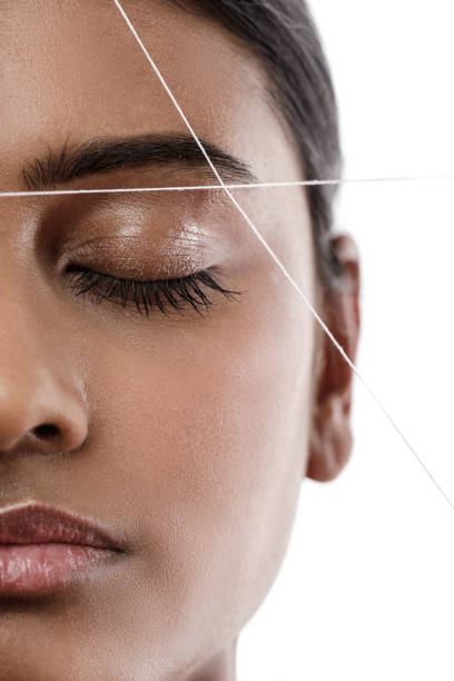 Eyebrow threading - epilation procedure for brow shape correction Close-up of Indian woman face with a thread. Eyebrow threading - epilation procedure for brow shape correction hair threading stock pictures, royalty-free photos & images