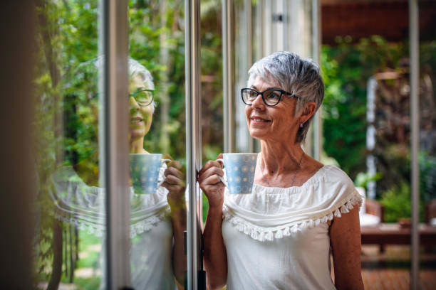 istock Serene Senior Woman with Coffee Looking Through Window 1189800602