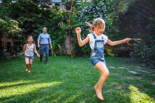 istock Young Sisters Playing in Family Backyard with Father 1189800630