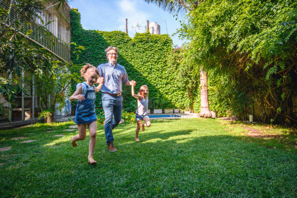 istock Smiling Father and Daughters Running Through Backyard 1189800631
