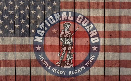 vintage american flag and national guard insignia painted on a weathered barn wall