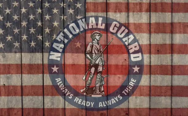vintage american flag and national guard insignia painted on a weathered barn wall