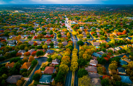 Autumn fall colors high above Suburb modern housing development in Austin Texas USA aerial drone view high above Suburb community neighborhood houses and homes rooftop and buildings. Real estate industry Birds Eye View