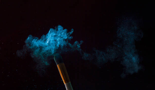 istock Make-up brush with blue powder explosion isolated on black background 1189809112