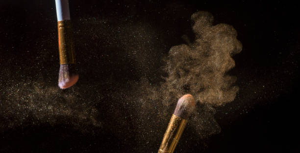 make-up brush with gold powder explosion isolated on black background - face powder exploding make up dust imagens e fotografias de stock