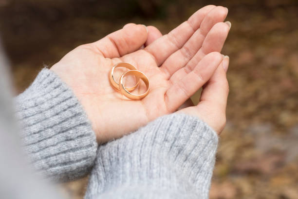 istock woman hand holding two wedding rings 1189809219