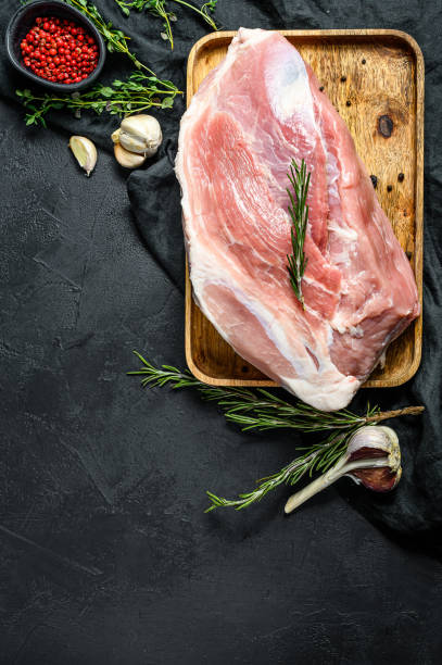 istock fresh pork cuts. Raw meat with spices.   shoulder butt part.. Black background. Top view 1189810089