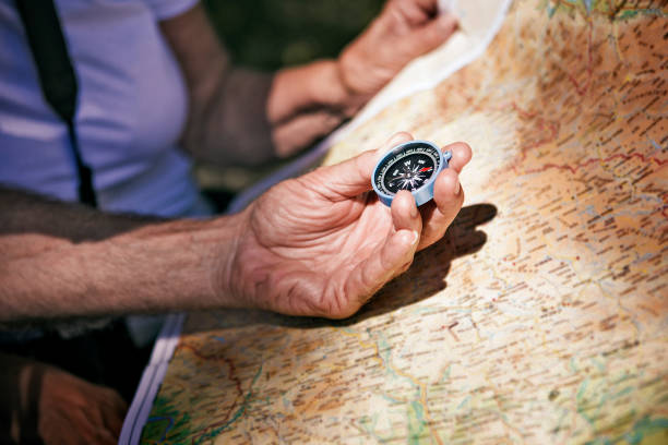 istock Senior hiker looking at hiking map navigating with compass 1189811457