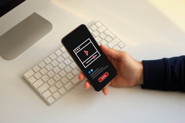 Hand holding smartphone with video player on the screen.