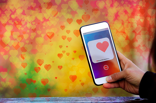 Finger of woman pushing heart icon on screen in mobile smartphone application.