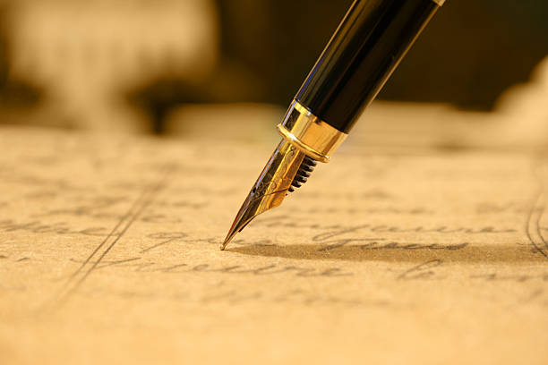 Close-up of a golden fountain pen writing Fountain pen on old post card. guest book photos stock pictures, royalty-free photos & images
