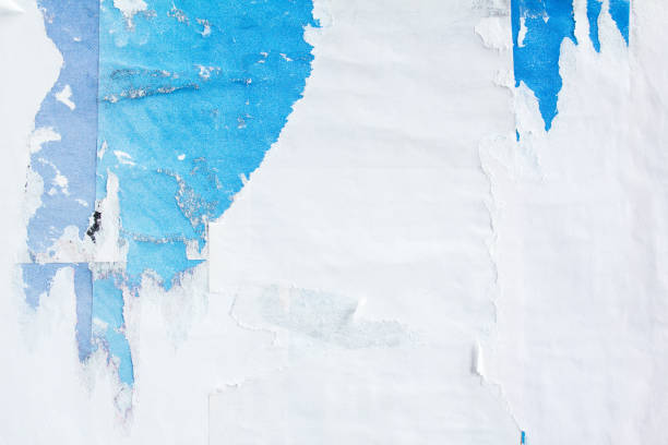 istock Old torn peeling blue and white paper posters on street billboard background. 1189820328