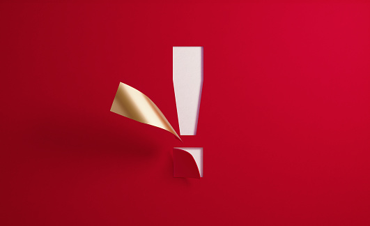 A golden exclamation point folding on red background. Horizontal composition with  copy space.