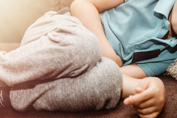 un chico vestido con una camiseta azul le pilla el estómago. concepto de medicina y salud, dolor de estómago. - diarrea fotografías e imágenes de stock