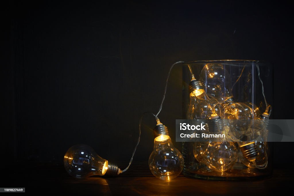 Glass vase filled with luminous bulbs on a wooden table, holiday concept Glass vase filled with luminous bulbs on wooden table, holiday concept Abstract Stock Photo