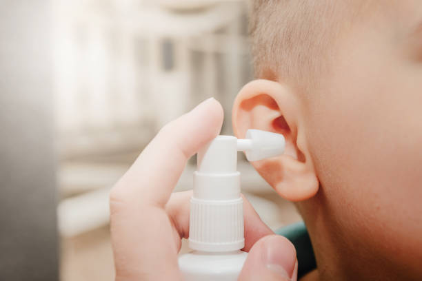 un genitore pulisce le orecchie di un bambino piccolo con una bomboletta spray. problemi di udito nei bambini, orecchie intasate. - cute little boys caucasian child foto e immagini stock