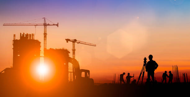 istock Silhouette of Survey Engineer and construction team working at site over blurred  industry background with Light fair.Create from multiple reference images together 1189829558
