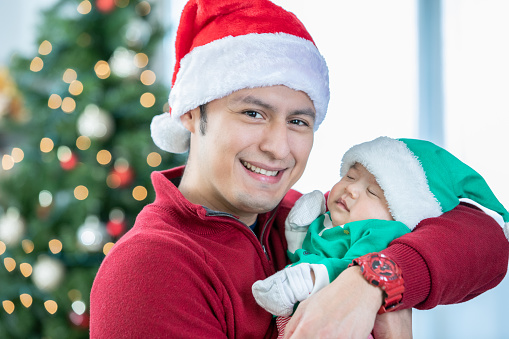 Father holding newborn baby and wearing festive hats