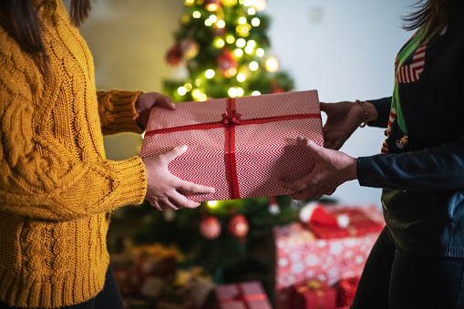 Unrecognizable people exchange Christmas gift during opening gifts.