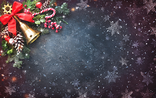Background with Christmas bells, fir tree, pine cones and holiday decoration on dark board