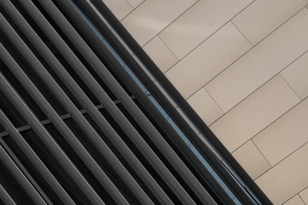 Angular view close-up of dark metal beams structure in fragment of building and smooth beige tiled wall